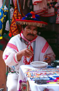 Colorful Huichol artisan working on a beaded necklace in Tepic.