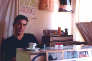 Nakis tattoo mannequins, top, in his studio. The old tattoo price list above his head in Albanian.