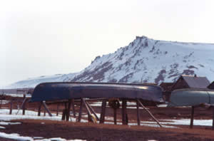 Old whale-hunting boats (angyapik) with Gambell Mountain and village in background. The Bering Sea is at far left.